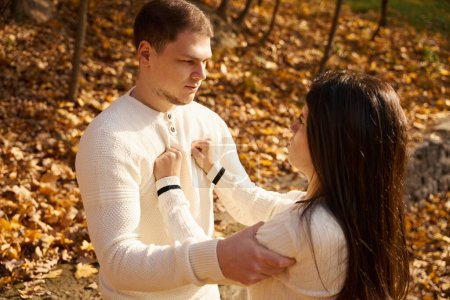 Photo for Young woman in a white sweater pushes away a slightly unshaven guy, they are standing on a park alley - Royalty Free Image