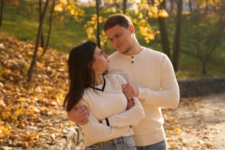 Téléchargez les photos : Un gars souriant avec un léger non rasé embrassé doucement sa petite amie, ils se détendent dans la nature - en image libre de droit