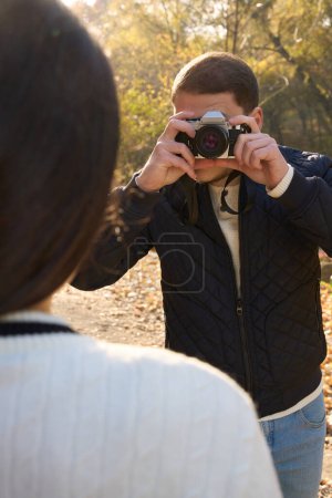 Téléchargez les photos : Guy en tenue décontractée tient un appareil photo sur son visage, il prend des photos de sa petite amie - en image libre de droit