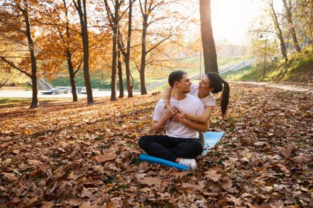 Téléchargez les photos : Jolie jeune femme serrant joyeusement son ami, ils sont assis sur le carimate dans le parc - en image libre de droit