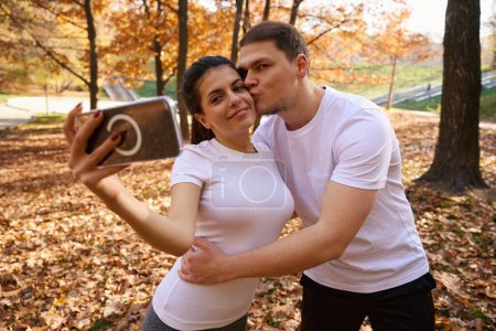 Photo for Pretty woman takes a selfie with her friend against the backdrop of an autumn landscape, guys in sportswear - Royalty Free Image
