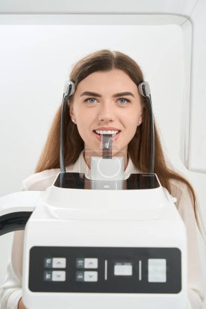 Foto de Paciente femenina posando para cámara durante tomografía computarizada de haz cónico de mandíbula inferior - Imagen libre de derechos