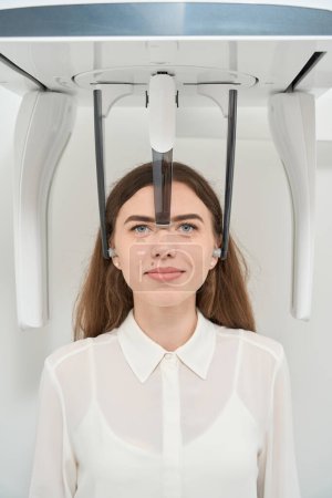 Photo for Young woman posing for camera during cone-beam computed tomography of upper jaw - Royalty Free Image