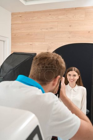 Foto de Estomatólogo toma imágenes de cara de paciente femenina contra fondo negro usando cámara digital - Imagen libre de derechos