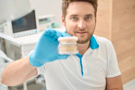 Photo for Portrait of young dentist in disposable nitrile glove holding model of the oral cavity - Royalty Free Image