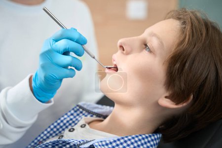 Téléchargez les photos : Garçon à la réception au cabinet dentaire, le médecin examine sa cavité buccale - en image libre de droit