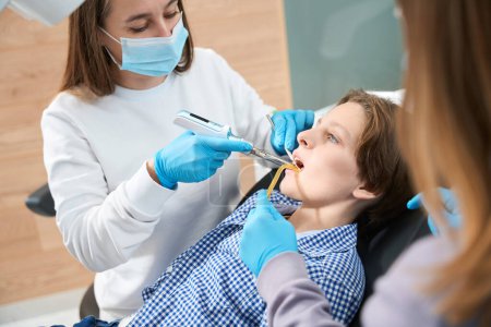 Foto de Mujer dentista en el lugar de trabajo trabaja con herramientas especiales, un asistente la ayuda - Imagen libre de derechos