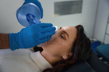 Photo for Woman with her eyes closed lies in the interior of an ambulance while a medical worker provides oxygen - Royalty Free Image