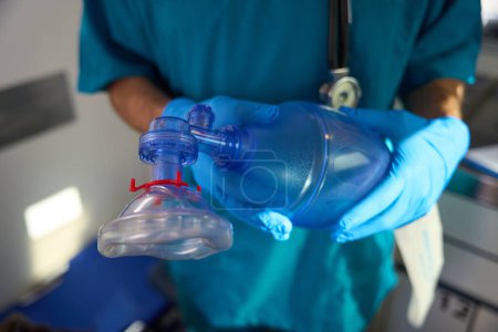 Photo for Man in sterile gloves holds an oxygen bag and a resuscitation mask with both hands - Royalty Free Image