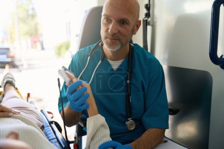 Photo for Focused doctor holding female hand while they are together in ambulance - Royalty Free Image