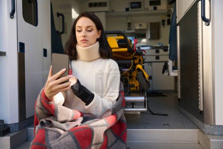 Foto de Triste paciente con el cuello inmovilizado levantó la mano a los ojos mientras presionaba la pantalla del gadget - Imagen libre de derechos