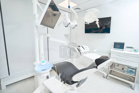 Foto de Silla de cuero vacía para paciente estomatológico con luz aérea en consultorio de dentista - Imagen libre de derechos