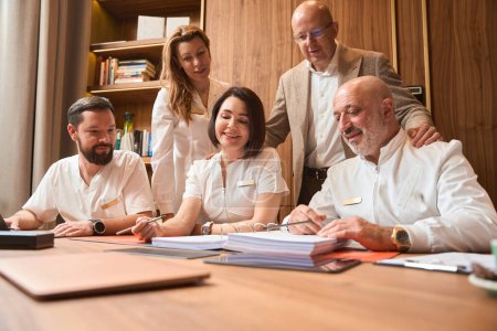 Foto de Team of doctors discusses a treatment plan at a professional meeting, colleagues are located in a large office - Imagen libre de derechos
