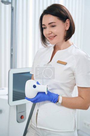 Téléchargez les photos : Pretty doctor holds an applicator of the BTL 600 device in her hands, a woman uses it for urological procedures - en image libre de droit