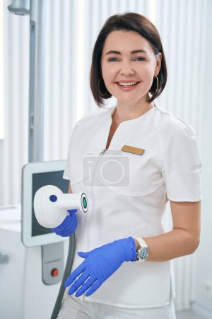 Téléchargez les photos : Doctor holds the applicator of BTL 600 shock wave therapy device in his hands, the woman is smiling and beautiful - en image libre de droit