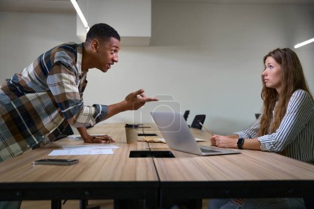 Téléchargez les photos : Side view of African American man arguing with his female colleague in the office - en image libre de droit