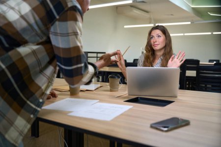 Téléchargez les photos : Young lady arguing with her male colleague in the office while working - en image libre de droit