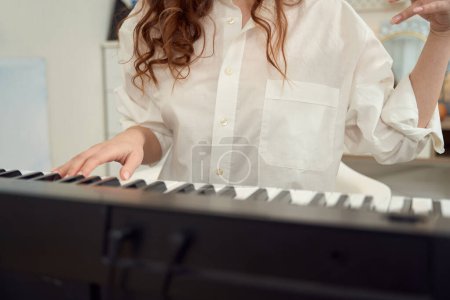 Téléchargez les photos : Cropped photo of professional female composer creating new musical composition on synthesizer - en image libre de droit