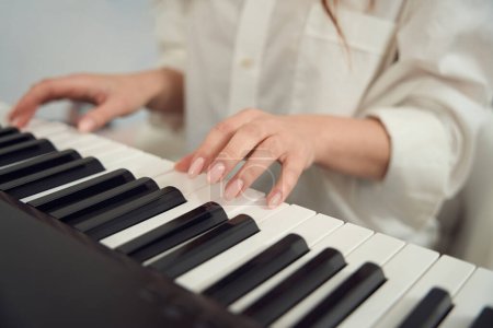 Téléchargez les photos : Cropped photo of professional female musician playing melody on electronic musical instrument - en image libre de droit