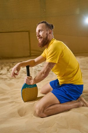 Photo for Relaxed tennis player holding racket with hand while taking breath during workout - Royalty Free Image