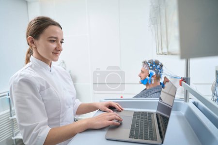 Photo for Doctor conducts a diagnostic procedure for EEG - electroencephalography to a middle-aged man, the diagnostician uses modern equipment - Royalty Free Image