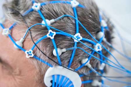 Téléchargez les photos : Gray-haired man on the diagnosis of EEG - electroencephalography, sensors are attached to his head - en image libre de droit