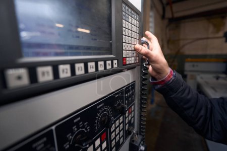 Photo for Man in standing in workshop near equipment, selecting command on control panel - Royalty Free Image