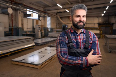 Photo for Portrait of smiling man in protective clothes standing in workshop, looking ahead - Royalty Free Image