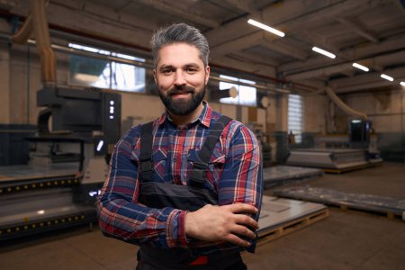 Téléchargez les photos : Portrait of smiling male in protective clothes standing in workshop, looking at the camera - en image libre de droit