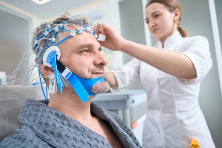 Photo for Patient undergoes a check-up in a modern clinic, the doctor performs a diagnostic procedure EEG - electroencephalography - Royalty Free Image