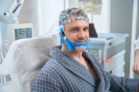 Téléchargez les photos : Man undergoes an EEG examination - electroencephalography in a medical clinic, around modern equipment - en image libre de droit