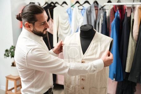 Téléchargez les photos : Experienced tailor checking fit of client waistcoat on dummy in his studio - en image libre de droit