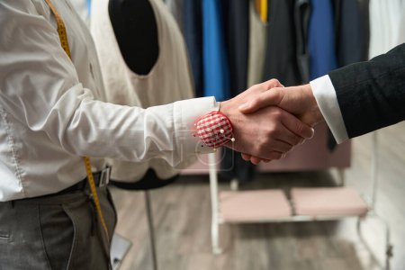 Foto de Cropped photo of fashion designer shaking hands with client in his atelier - Imagen libre de derechos