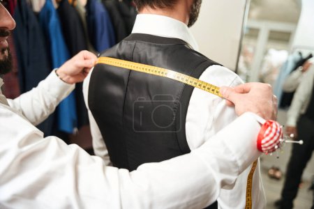 Photo for Cropped photo of tailor measuring shoulder width of customer with tape measure - Royalty Free Image