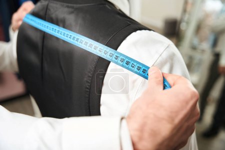 Photo for Cropped photo of experienced clothier measuring client shoulder width with tape measure - Royalty Free Image