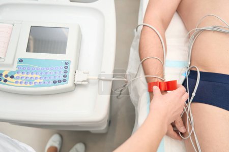 Foto de Imagen de cerca del médico está utilizando cardiógrafo y electrodos en la mano del paciente para el diagnóstico de latidos cardíacos en la clínica - Imagen libre de derechos