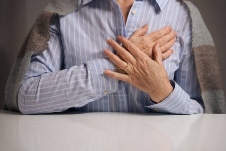 Foto de Pensionista de edad avanzada está experimentando dolor en el esternón, se puso las manos en el pecho - Imagen libre de derechos