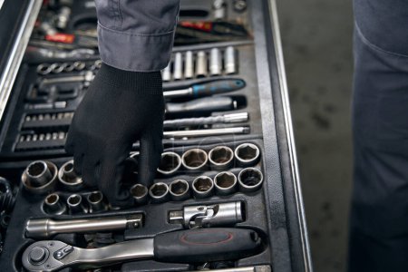 Foto de Mecánico en ropa protectora y guantes de pie en el montaje de neumáticos e instrumentos de toma para el trabajo - Imagen libre de derechos