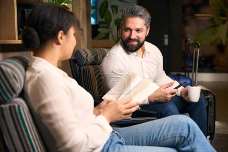 Foto de Sonriendo complacido hombre elegante hablando con su compañera femenina en la sala de estar - Imagen libre de derechos