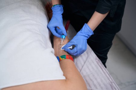 Téléchargez les photos : Travailleur médical dans des gants de protection et un manteau tenant la seringue et prenant le sang de la veine du patient - en image libre de droit