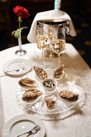 Téléchargez les photos : Ensemble d'huîtres est servi pour deux dans une chambre d'hôtel de luxe, une rose rouge et du champagne sont sur la table - en image libre de droit