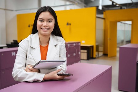 Photo for Waist-up portrait of happy corporate worker with smartphone and laptop in hands looking before her - Royalty Free Image