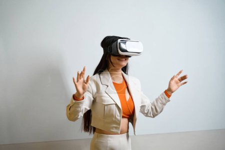 Foto de Sonriente trabajador de oficina feliz en auriculares de realidad virtual de pie contra la pared con pizarra - Imagen libre de derechos