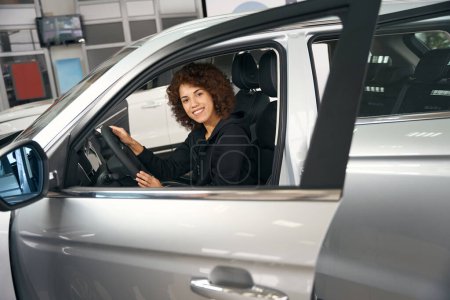Foto de Comprador multirracial feliz se sienta en el salón de un coche nuevo, ella elige el modelo correcto - Imagen libre de derechos