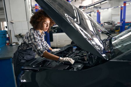 Photo for Employee of the auto repair shop inspects the car under the hood, the car is being serviced - Royalty Free Image