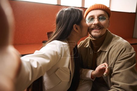 Téléchargez les photos : Femme romantique donnant baiser à jeune homme heureux tout en prenant selfie avec caméra smartphone - en image libre de droit