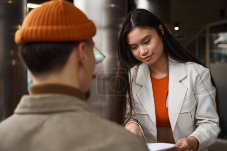 Photo for Calm focused young female company employee demonstrating business documentation to her coworker - Royalty Free Image