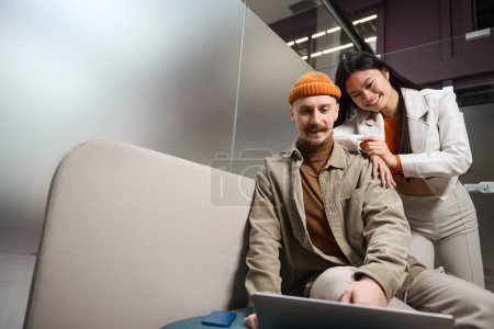 Téléchargez les photos : Plaisir caucasien mâle et joyeux asiatique femelle regarder la vidéo sur ordinateur portable écran - en image libre de droit