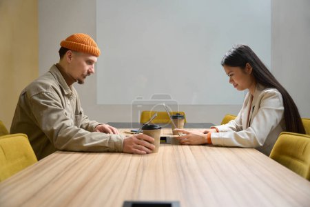 Téléchargez les photos : Travailleurs d'entreprise concentrés assis au bureau tout en travaillant sur des ordinateurs portables - en image libre de droit