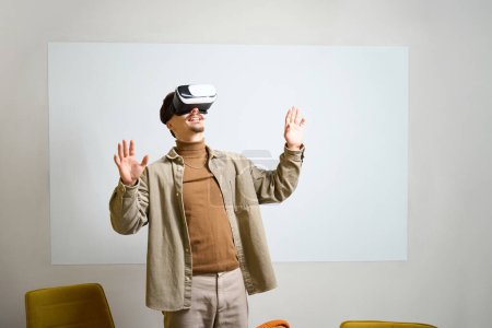 Téléchargez les photos : Sourire joyeux employé caucasien en réalité virtuelle casque debout au bureau - en image libre de droit
